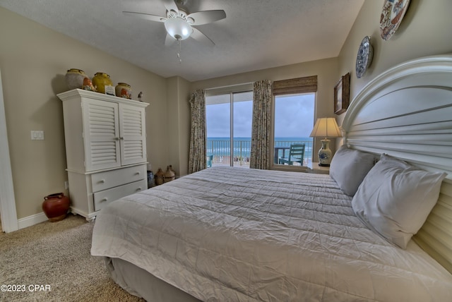 bedroom featuring light carpet, a textured ceiling, access to outside, ceiling fan, and a water view