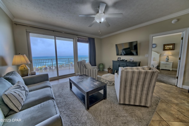 tiled living room with ceiling fan, ornamental molding, and a textured ceiling