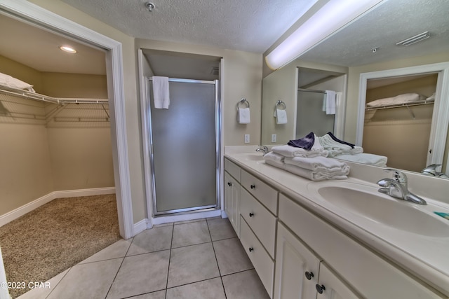 bathroom featuring vanity, a textured ceiling, tile patterned floors, and an enclosed shower