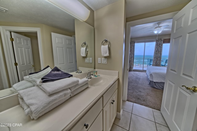 bathroom featuring ceiling fan, tile patterned flooring, a textured ceiling, a water view, and vanity