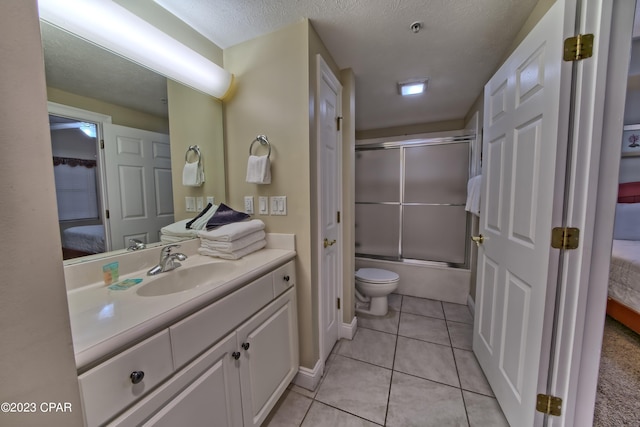 full bathroom with tile patterned floors, a textured ceiling, toilet, shower / bath combination with glass door, and vanity