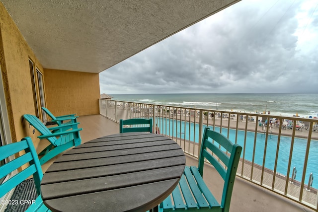 balcony with a water view and a view of the beach