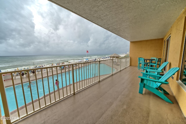 balcony featuring a view of the beach and a water view