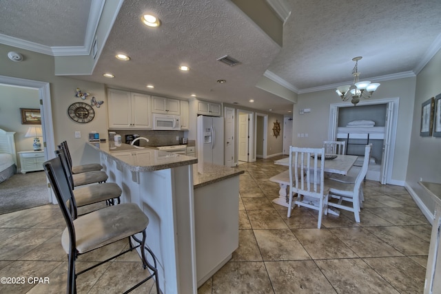 kitchen with kitchen peninsula, a textured ceiling, white appliances, crown molding, and hanging light fixtures