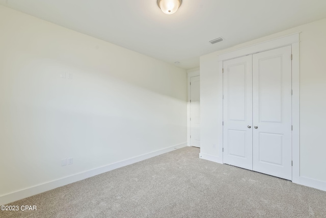 unfurnished bedroom with a closet and light colored carpet