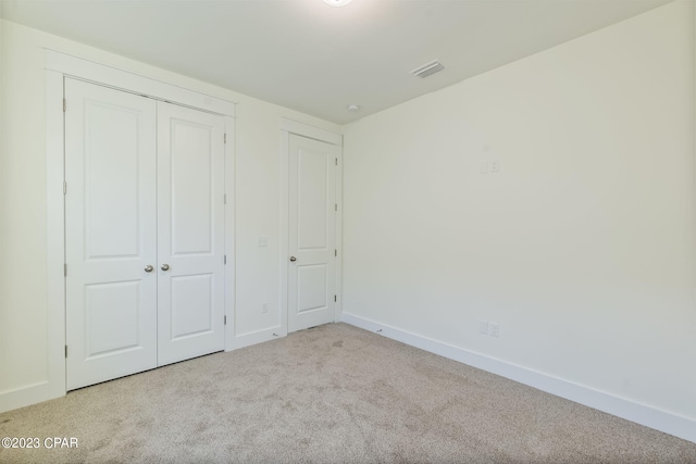 unfurnished bedroom with light carpet and a closet