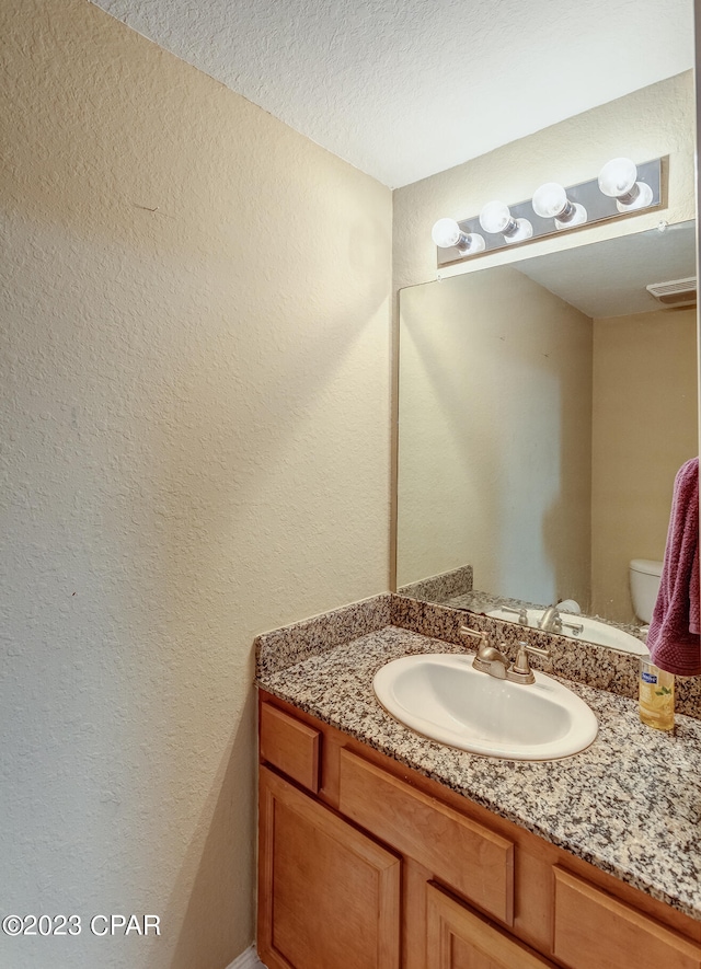 bathroom with vanity, a textured ceiling, and toilet