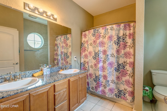 bathroom with tile floors, double vanity, and toilet