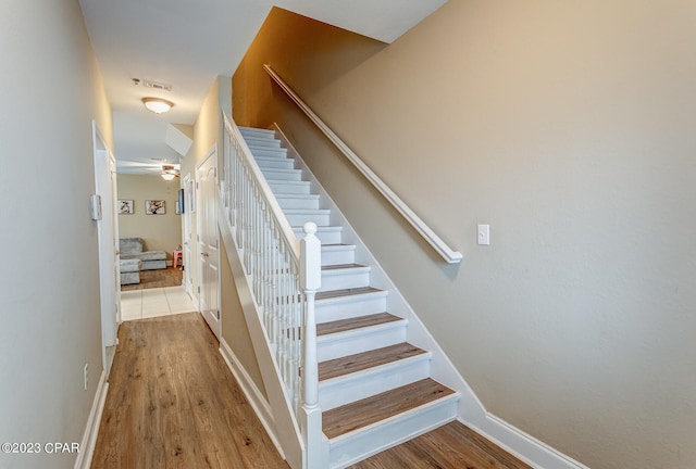 stairway featuring ceiling fan and light wood-type flooring