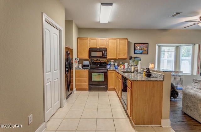 kitchen featuring kitchen peninsula, sink, ceiling fan, dark stone counters, and black appliances