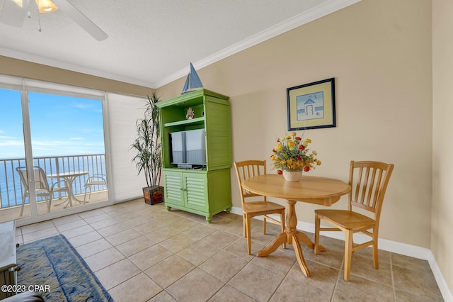 dining area featuring a wealth of natural light, crown molding, a water view, and light tile patterned floors