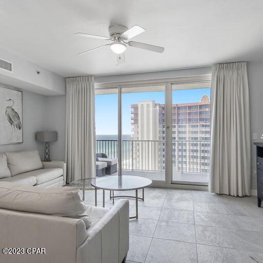 living room featuring a water view, light tile flooring, and ceiling fan