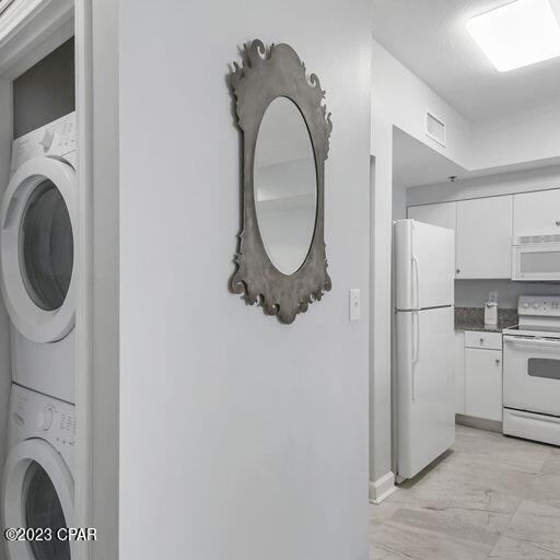 washroom with stacked washer and clothes dryer and light hardwood / wood-style flooring