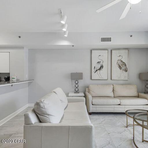 tiled living room featuring rail lighting and ceiling fan