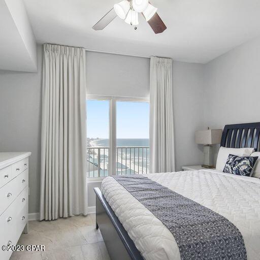 tiled bedroom with access to exterior, ceiling fan, and a water view