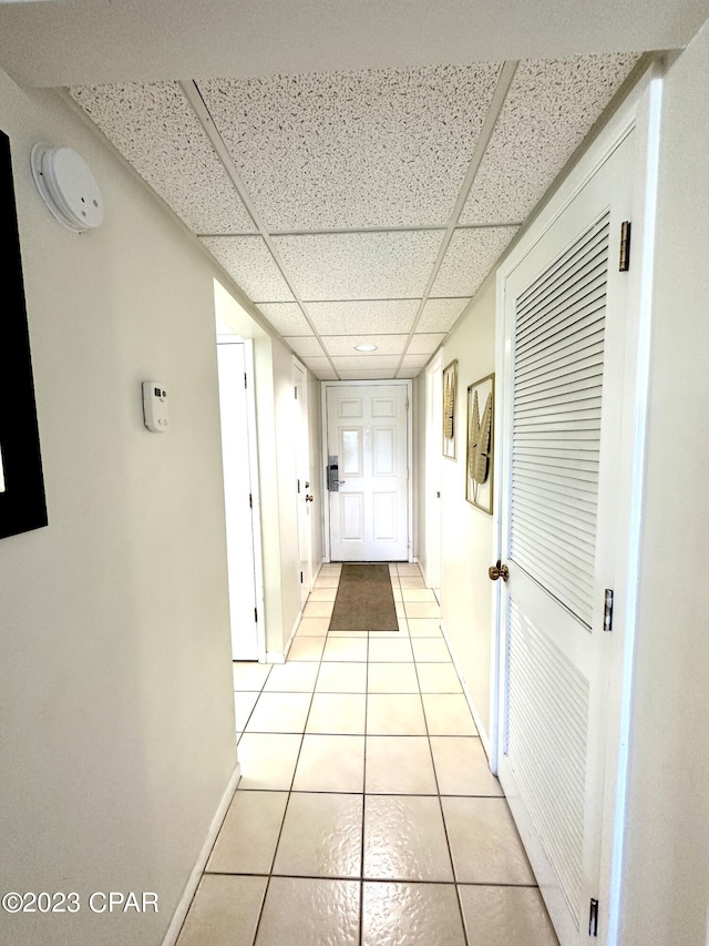 hall with light tile flooring and a drop ceiling