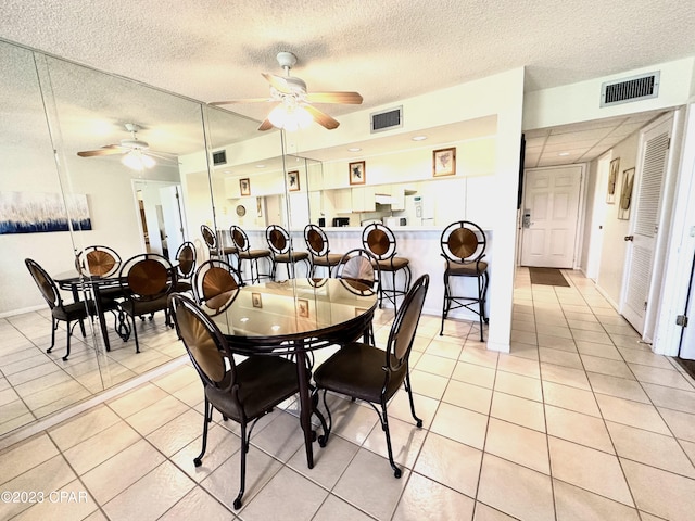 tiled dining room featuring a textured ceiling and ceiling fan