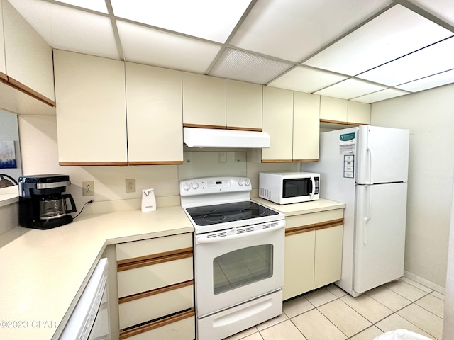 kitchen with light tile floors, cream cabinetry, white appliances, and a drop ceiling