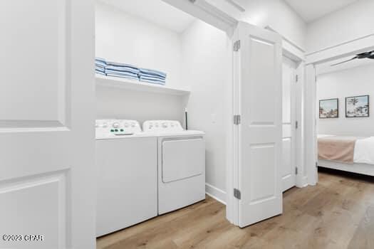 clothes washing area with washer and dryer and light wood-type flooring