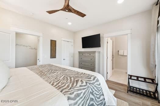 bedroom featuring ceiling fan, ensuite bath, and light wood-type flooring