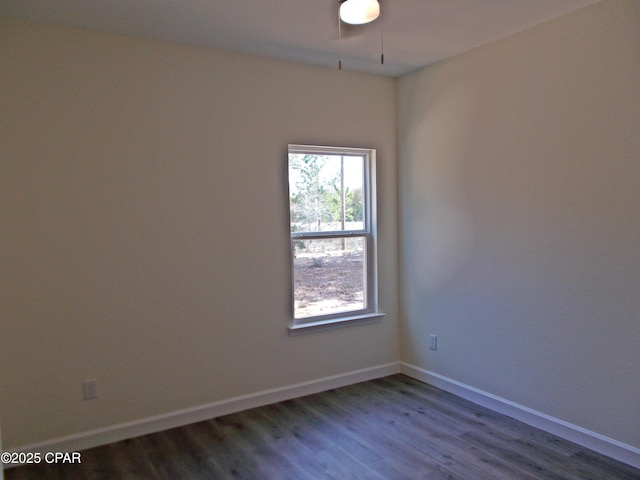 spare room featuring baseboards and dark wood finished floors