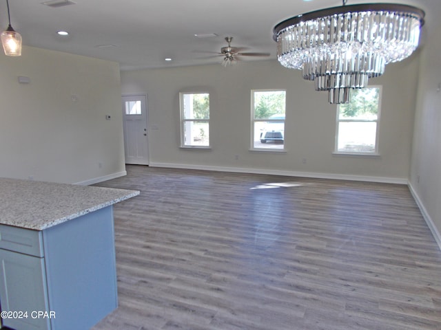 unfurnished dining area featuring dark wood-type flooring and ceiling fan with notable chandelier