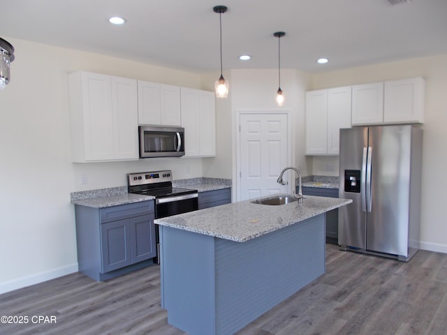 kitchen featuring stainless steel appliances, wood finished floors, a sink, and white cabinets