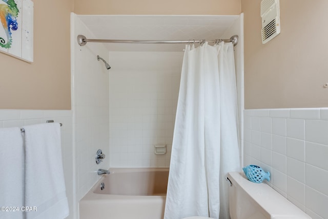 bathroom with shower / bath combination with curtain and toilet