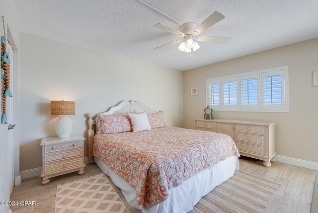 bedroom featuring a textured ceiling, light wood-type flooring, and ceiling fan