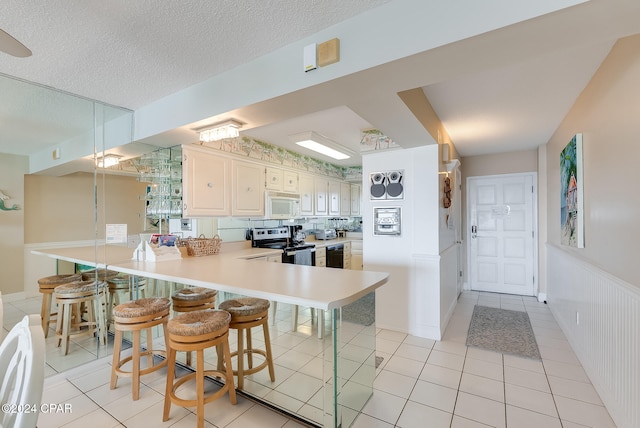 kitchen featuring kitchen peninsula, pendant lighting, a textured ceiling, a breakfast bar area, and electric stove