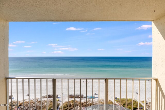 balcony with a water view and a view of the beach