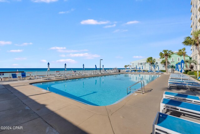 view of pool with a patio area and a water view