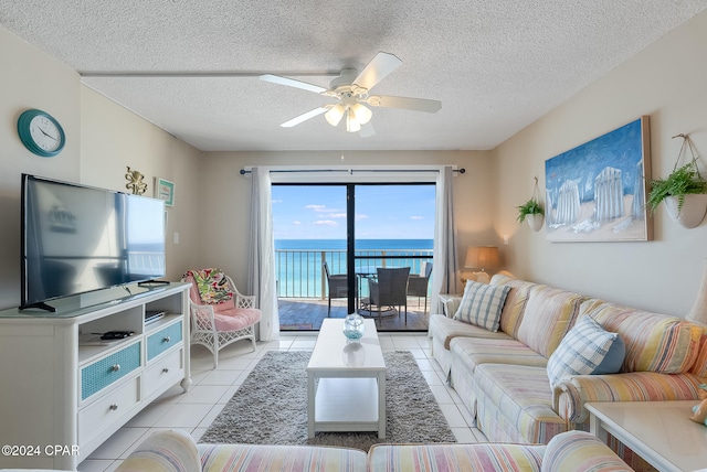 tiled living room with a textured ceiling, a water view, and ceiling fan