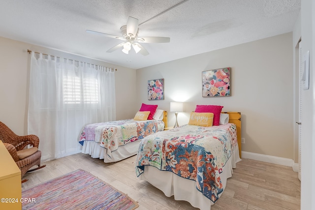 bedroom featuring ceiling fan, a textured ceiling, and light wood-type flooring