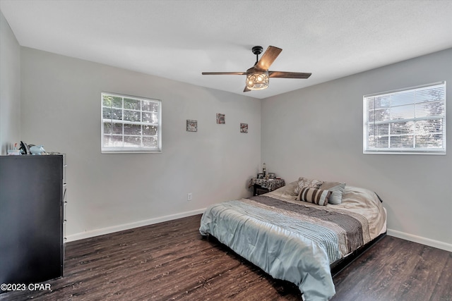 bedroom with ceiling fan, a textured ceiling, and dark hardwood / wood-style flooring