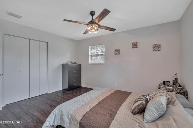 bedroom with ceiling fan, dark wood-type flooring, and a closet