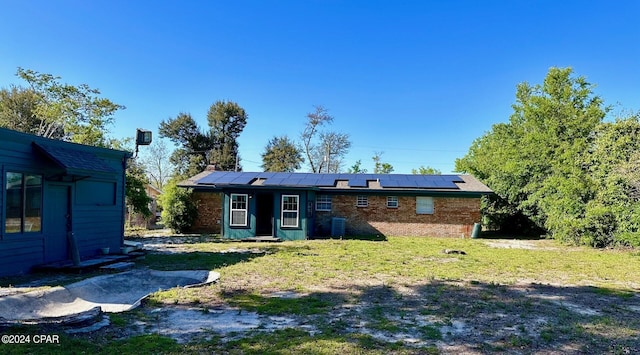 back of property with a yard and solar panels