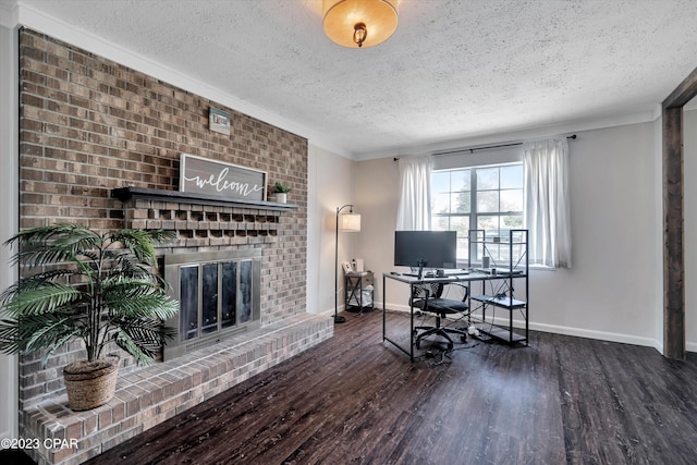 home office with crown molding, a brick fireplace, dark hardwood / wood-style floors, and a textured ceiling