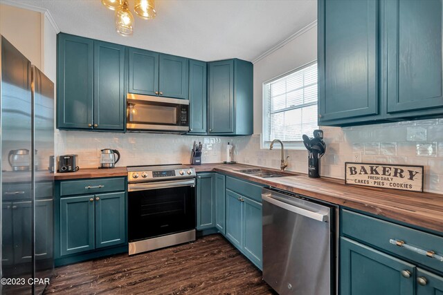 kitchen featuring wood counters, appliances with stainless steel finishes, blue cabinetry, and sink