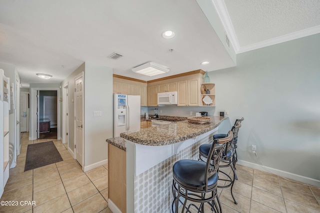 kitchen featuring white appliances, kitchen peninsula, light brown cabinetry, and light tile patterned flooring