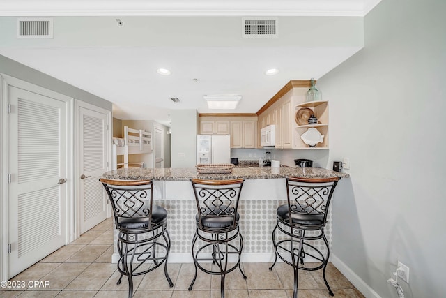 kitchen featuring a kitchen breakfast bar, white appliances, and kitchen peninsula