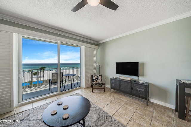 tiled living room featuring a water view, a textured ceiling, ceiling fan, and crown molding