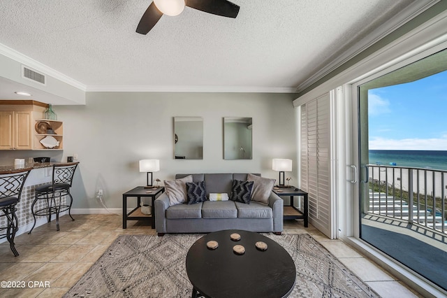 living room featuring a textured ceiling, crown molding, a water view, and ceiling fan