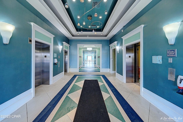 hallway with a raised ceiling, elevator, and light tile patterned flooring