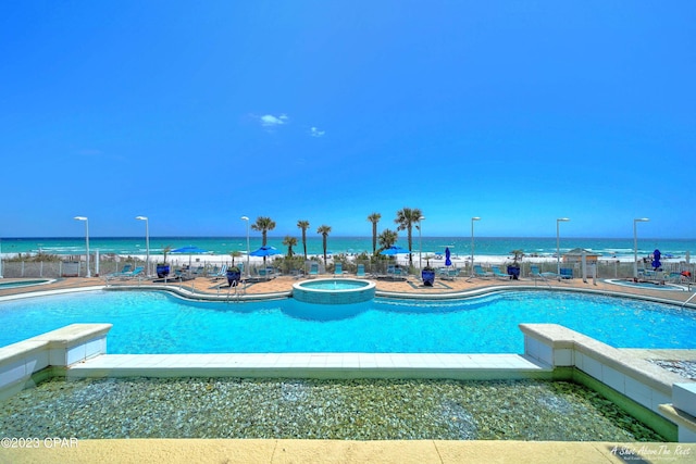 view of pool with a patio, a water view, and an in ground hot tub