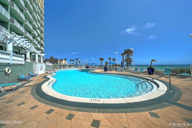 view of swimming pool with a water view and a patio area