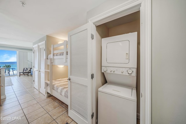 washroom featuring stacked washer and dryer and light tile patterned floors