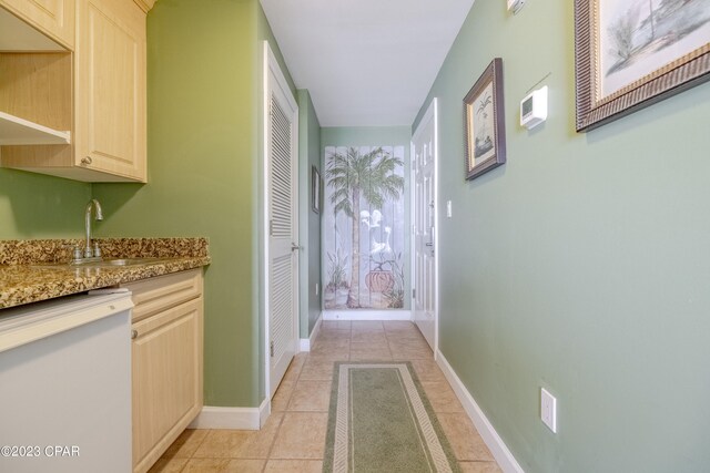 corridor featuring light tile patterned floors and sink