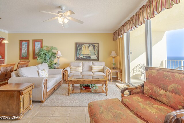 tiled living room featuring ceiling fan, a textured ceiling, ornamental molding, and a water view