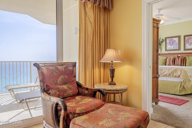 living area featuring a water view, ornamental molding, ceiling fan, and light colored carpet